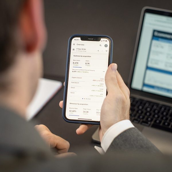 Person using a mobile app on a smartphone next to a laptop