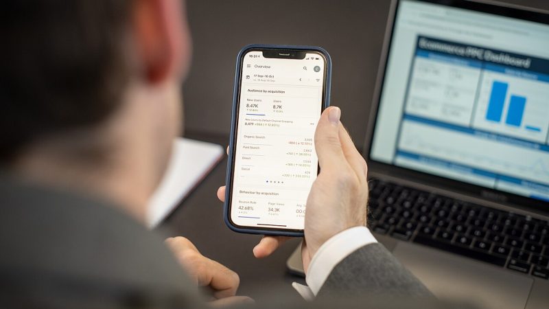 Person using a mobile app on a smartphone next to a laptop